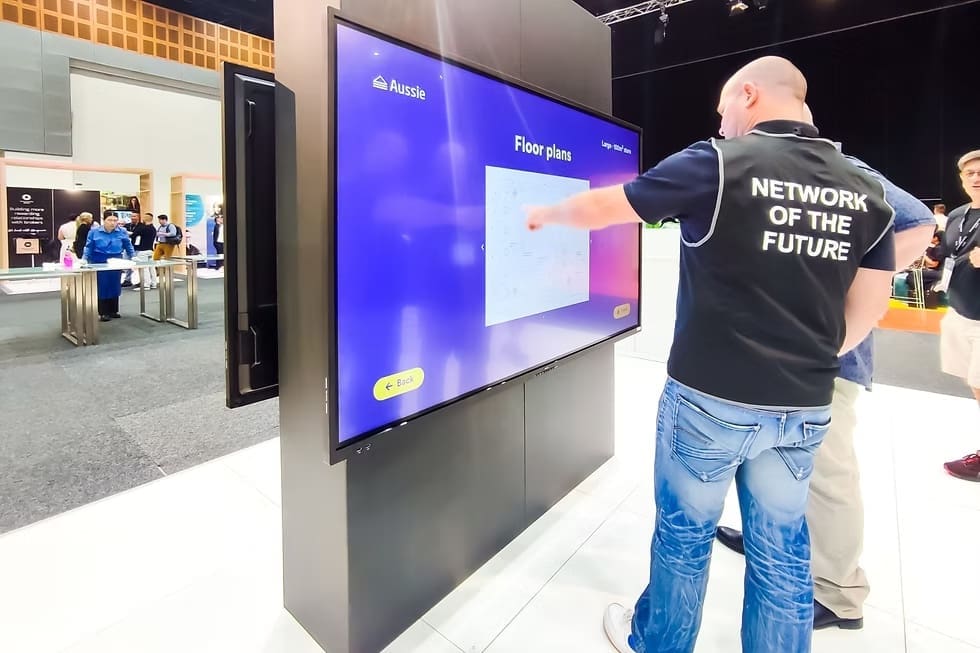 Interactive LED display at an expo event showing digital floor plans with attendees engaging in front.
