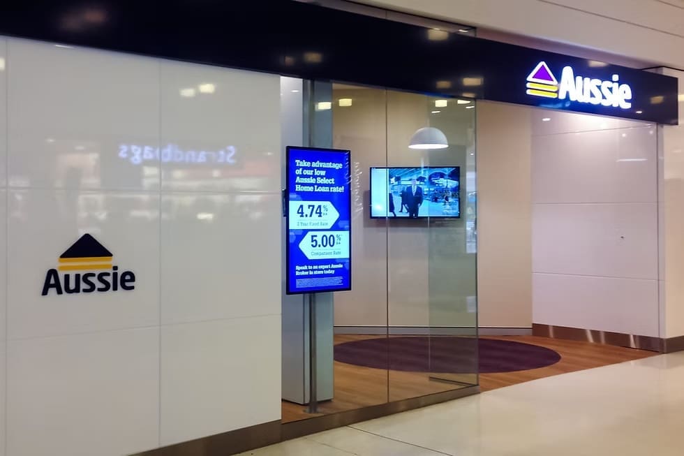 Exterior of Aussie Home Loans branch showcasing transparent LED window display advertising current home loan rates.