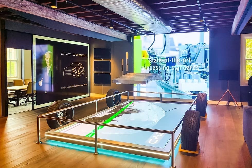 BYD automotive showroom featuring LED screens displaying car design visuals and production standards.