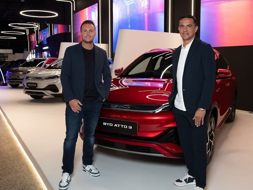 Two people standing beside a BYD ATTO 3 vehicle at the BYD Megastore, surrounded by LED display walls.