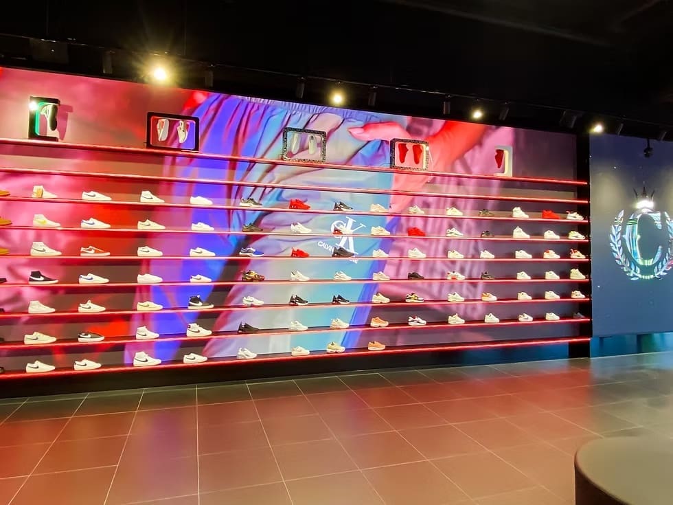 Culture Kings retail display wall lined with sneakers and a full-length LED video backdrop.