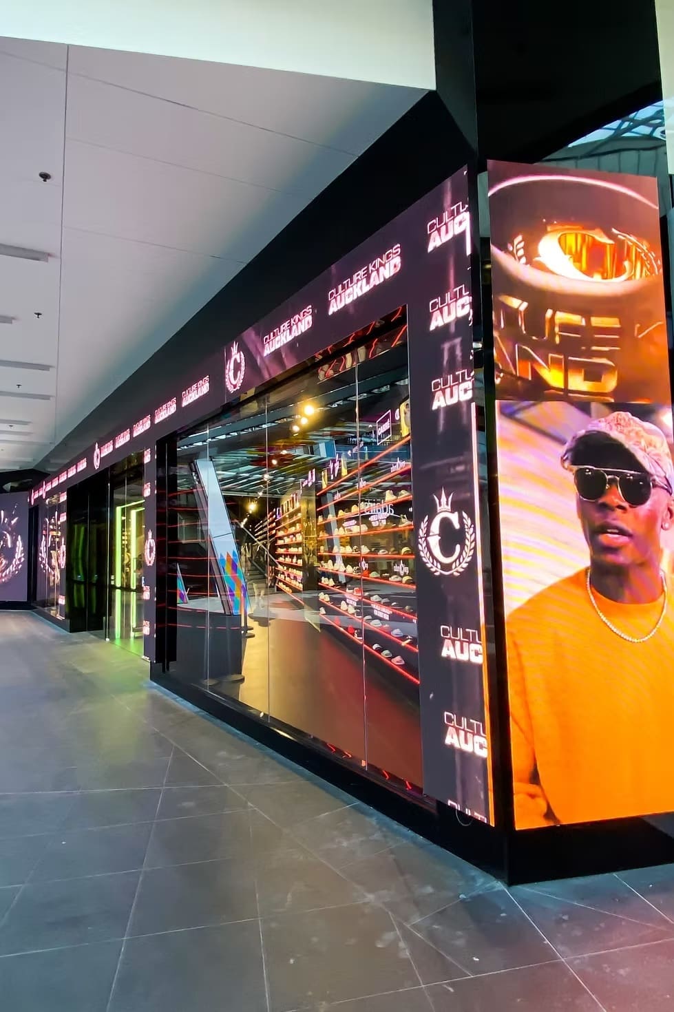 Exterior of Culture Kings Auckland store featuring full glass façade with LED signage and video displays.