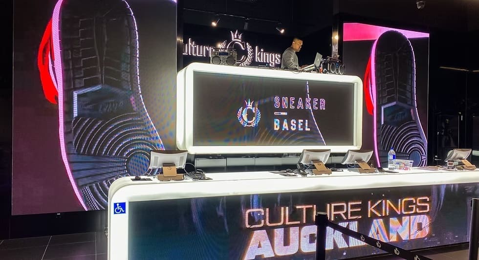 Culture Kings Auckland DJ booth setup with LED screens displaying Sneaker Basel branding and sneaker sole visuals.