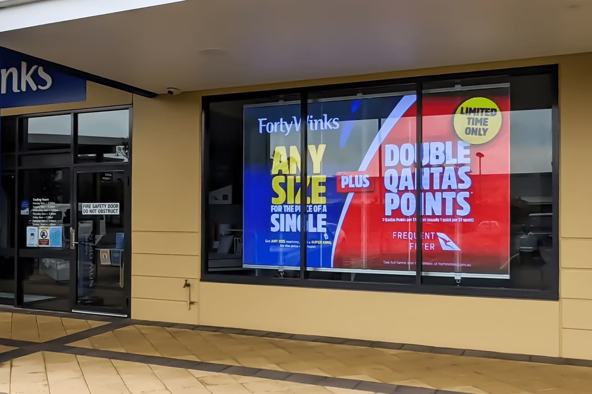 Forty Winks storefront with LED window display promoting mattress sale and Qantas Points offer.