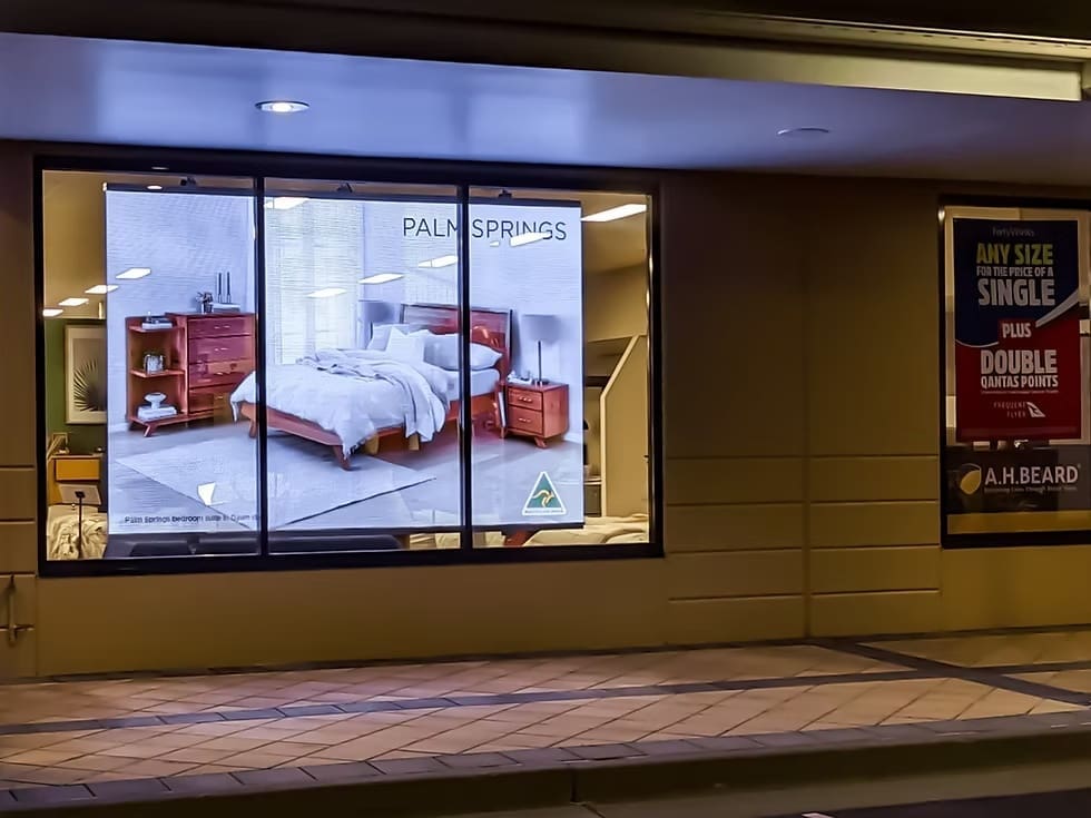 Forty Winks storefront window displaying Palm Springs bedroom suite advertisement beside Qantas Points signage.