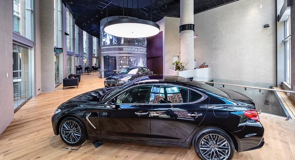 Luxury Genesis showroom featuring sleek black sedan and digital curved LED display wall.