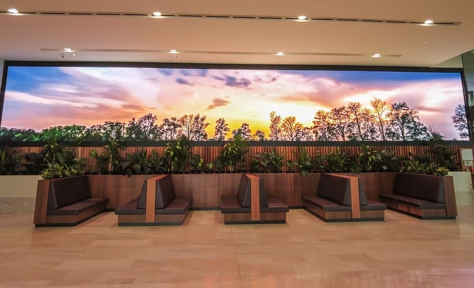Panoramic LED wall display at MOBO Rooftop showing a scenic sunset landscape behind booth seating and plants.