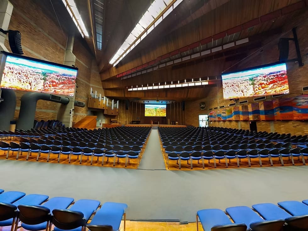 Auditorium at the University of Newcastle featuring LED screens displaying natural scenery for presentation setup.
