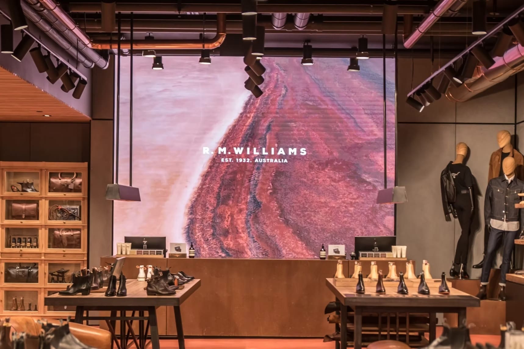 R.M. Williams retail store interior with large LED video wall displaying Australian landscape visuals.
