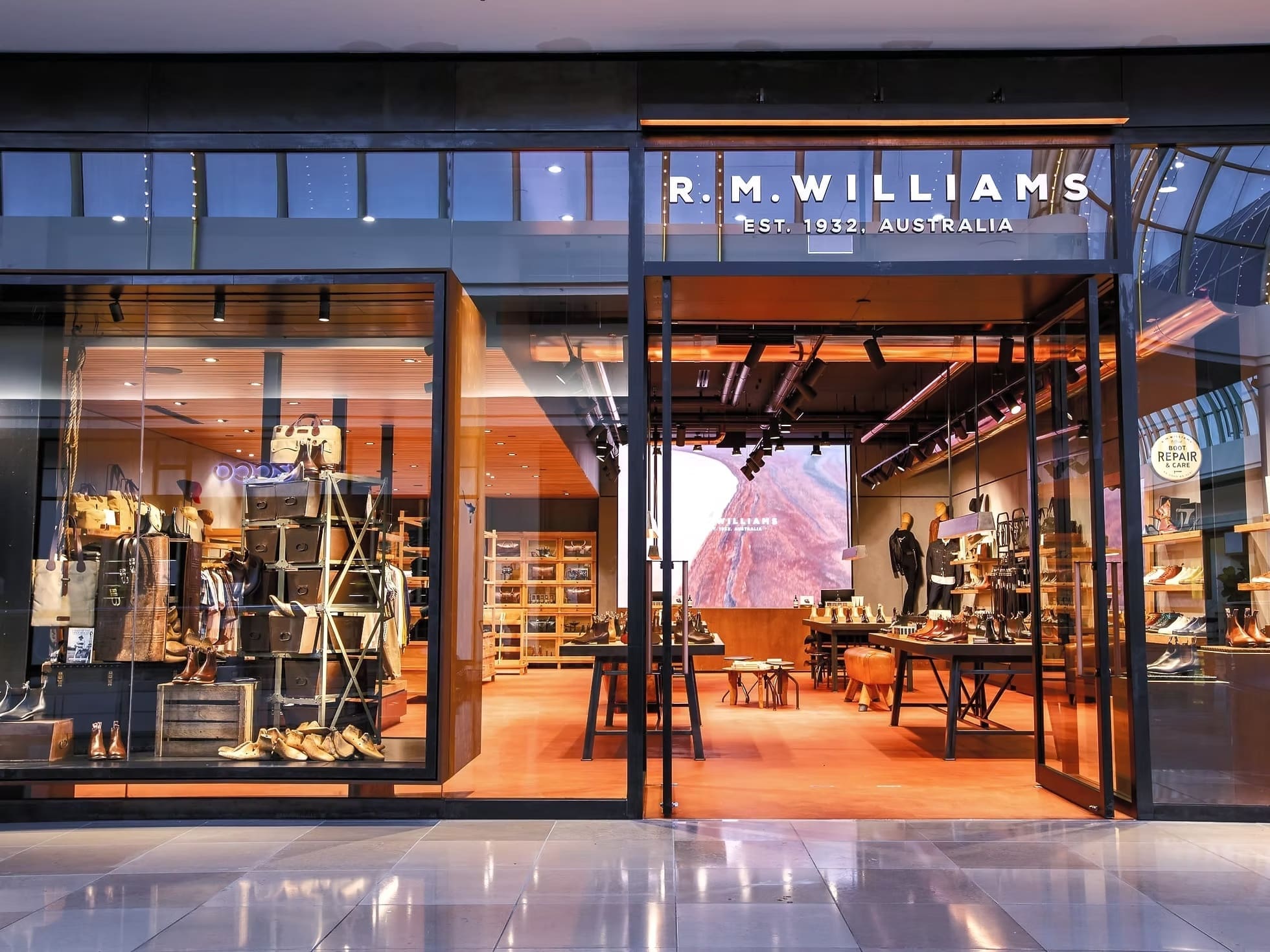 Inside R.M. Williams store featuring product displays and a large LED wall showing natural textures.