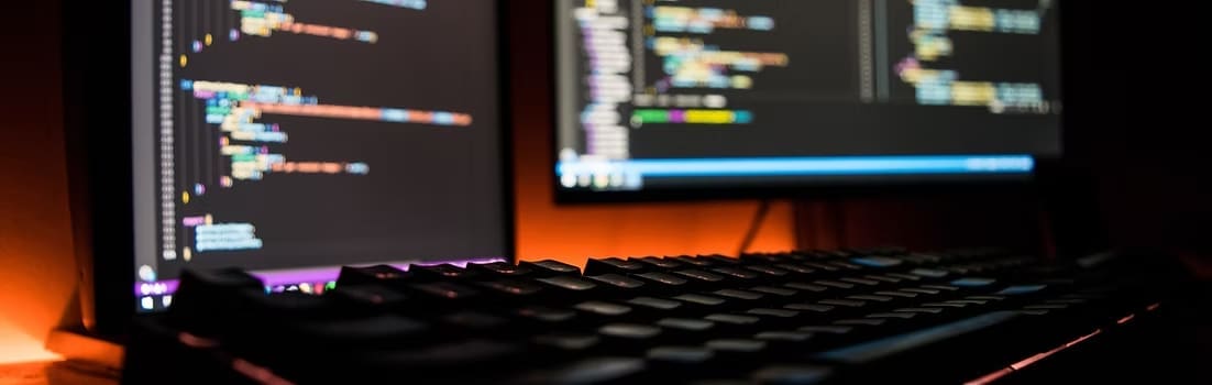 Close-up photo of a keyboard and monitor with code, symbolizing cybersecurity and data protection.